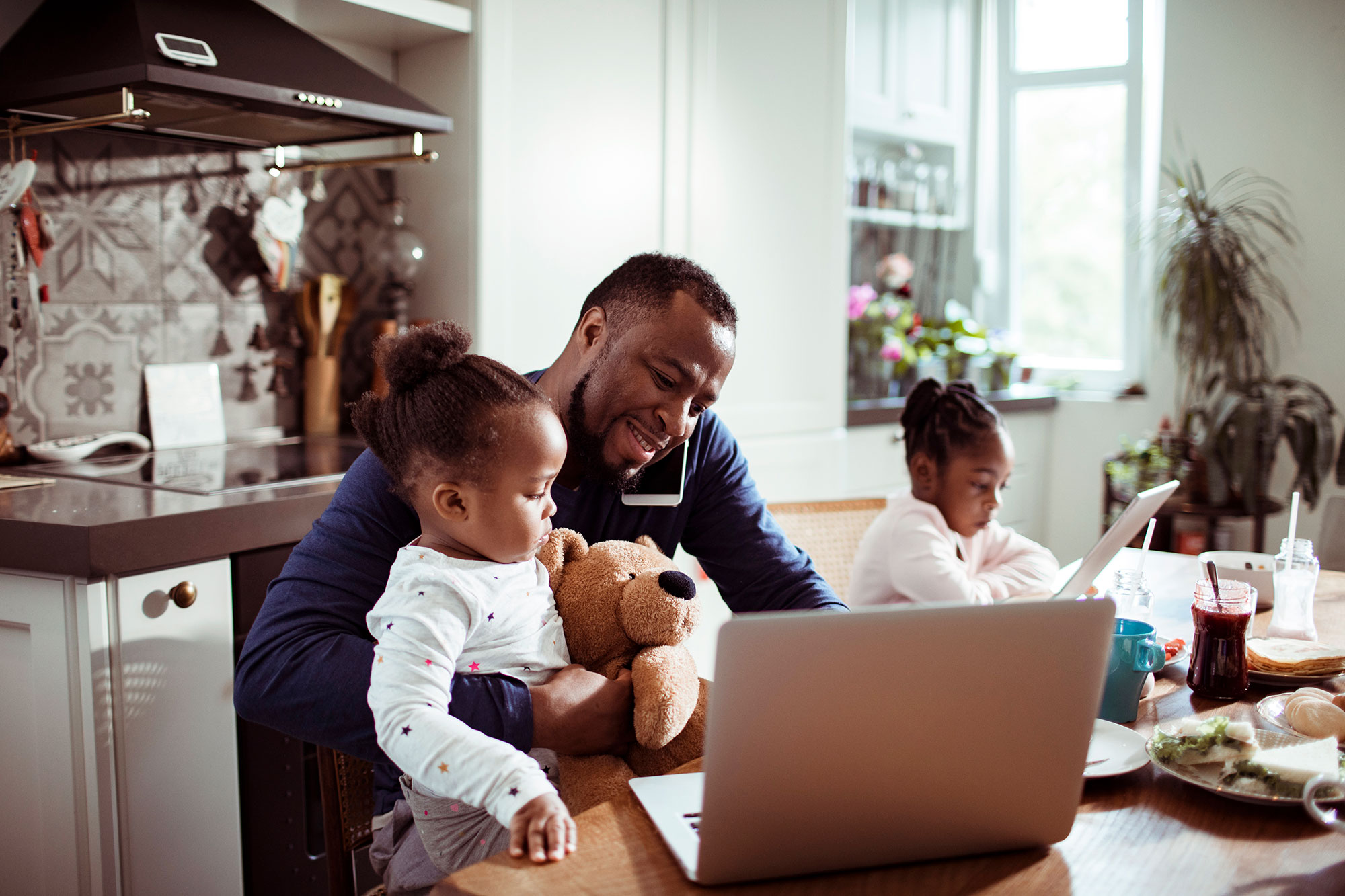 A dad reporting a claim by phone at a busy kitchen table